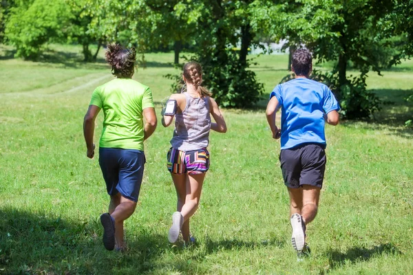 Mujer y dos jóvenes corriendo en el parque — Foto de Stock