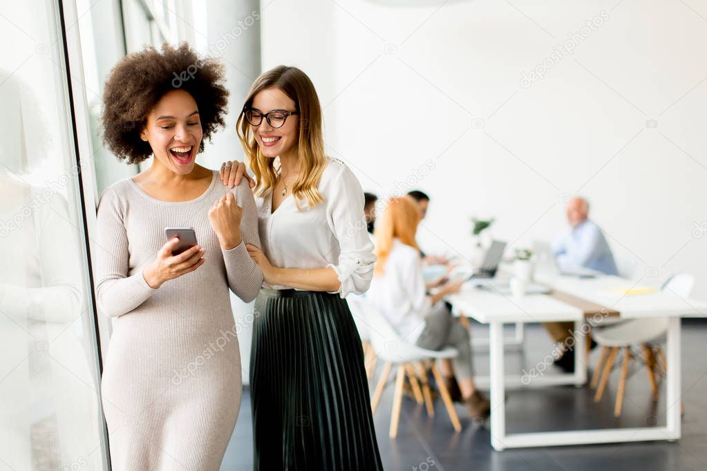 Pretty young multiethnic women with moble phone in the office