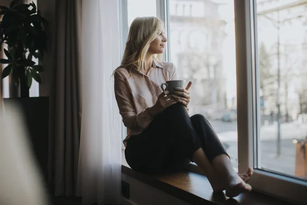 Blonde Junge Frau Entspannt Sich Und Trinkt Kaffee Fenster — Stockfoto