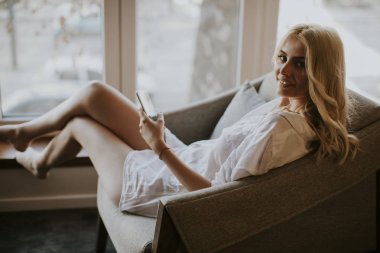 Koltukta oturan ve cep telefonuyla odaya genç kadın