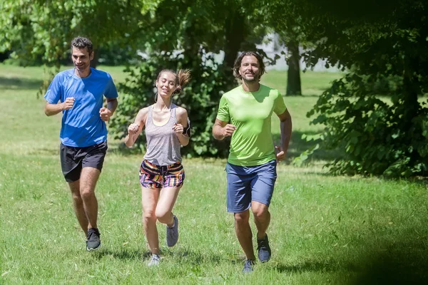 Woman and two young men running in the park at summer