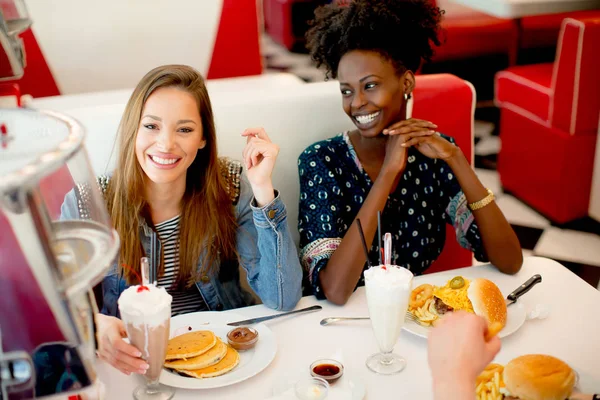 食べる民族の女友達 食堂のテーブルでファーストフードし 楽しい時を過す — ストック写真