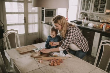 Hamile kadın ve küçük kızı rustik mutfakta yemek hazırlama