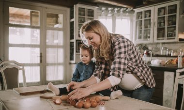 Hamile kadın ve küçük kızı rustik mutfakta yemek hazırlama