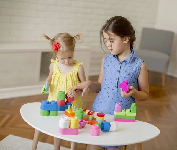 Дві маленькі дівчата грають з іграшками в кімнаті — стокове фото