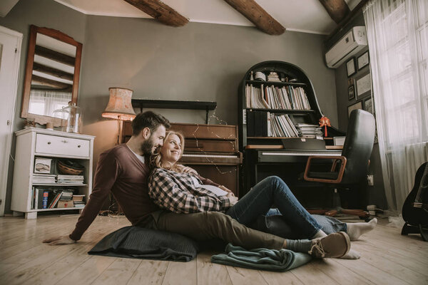 Pregnant woman with a husband sitting on the floor in the room