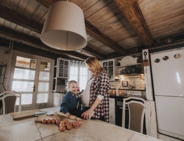 Hamile kadın ve küçük kızı rustik mutfakta makarna hazırlama