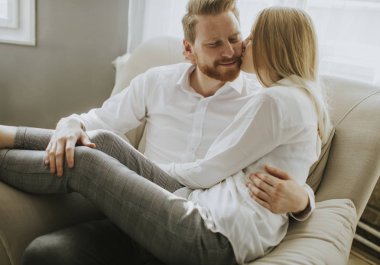 Kanepede oturan ve kanepeye sarılma sevgi dolu genç Çift