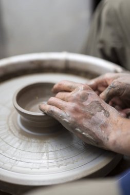 Manzaraya bir sanatçı kil çömlek bir spin tekerlek üzerinde yapar.