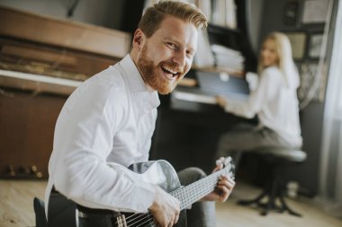 Yakışıklı bir erkek gitarist tarafından eşlik genç piyanist