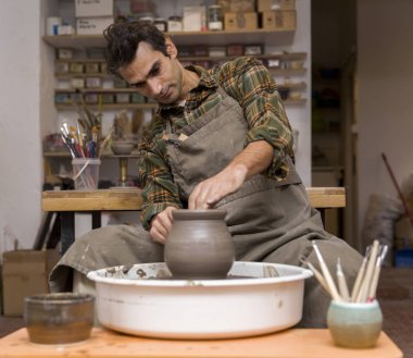 Manzaraya bir sanatçı kil çömlek bir spin tekerlek üzerinde yapar.