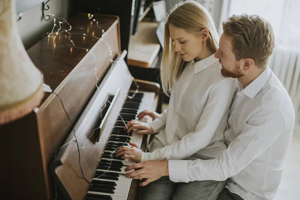 Loving couple playing piano in the room at home