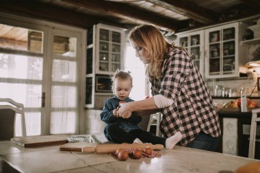 Hamile kadın ve küçük kızı rustik mutfakta makarna hazırlama