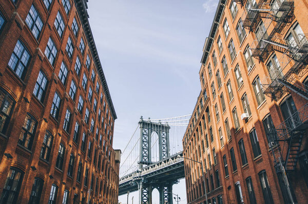 Manhattan bridge seen from a red brick buildings in Brooklyn street in perspective, New York, USA