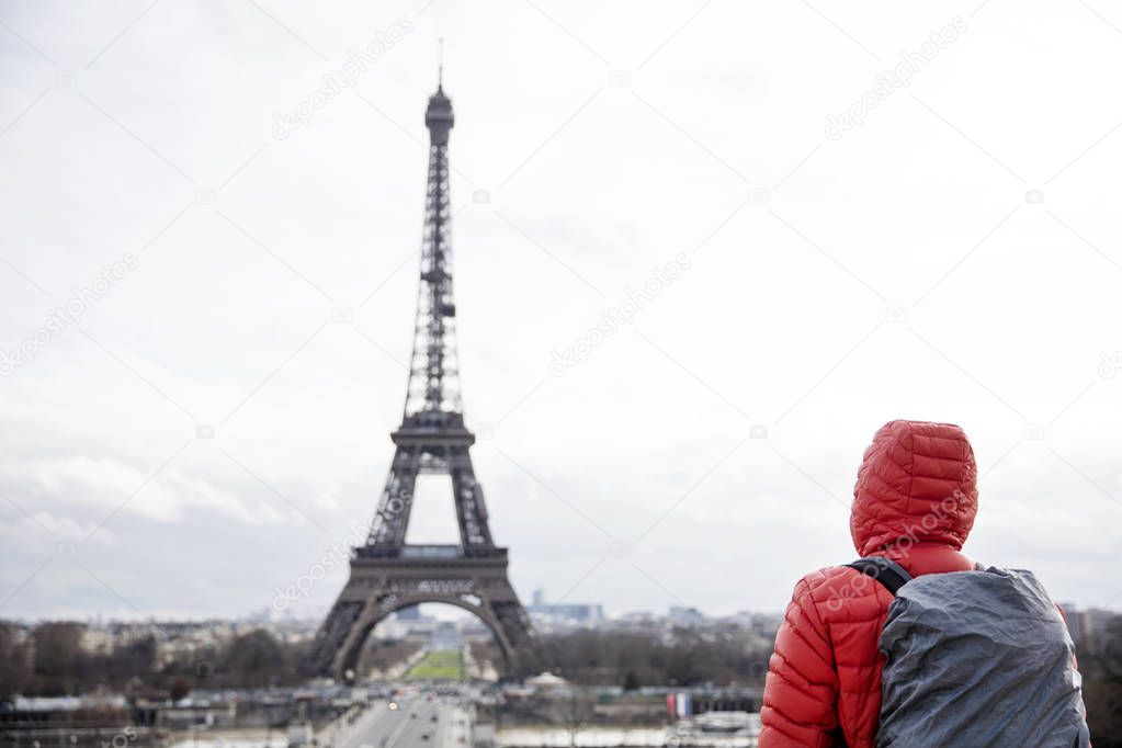 Young man with backpack looking at Eiffel tower in Paris, France