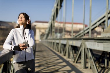 Kadın köprüde bir duraklama ve dinle müzik sonra egzersiz yapma