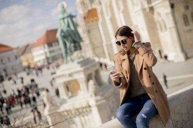 Açık ve kullanma cep telefonu oturan trendy genç kadın görüntüleme