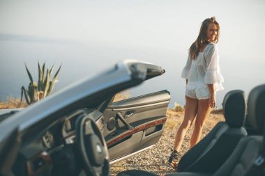 Sahilde beyaz cabriolet arabayla genç ve güzel kadın