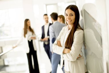 Genç işkadını ofis ve arka planda konuşurken diğer genç iş adamları ayakta