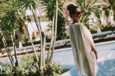 Yüzme Havuzu yanında duran ve güneşin tadını genç ve güzel kadın