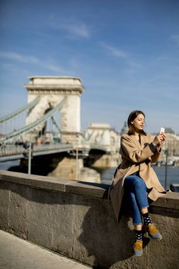 Zincir köprü, Budapeşte, Macaristan için arka plan ile cep telefonu kullanan genç kadın