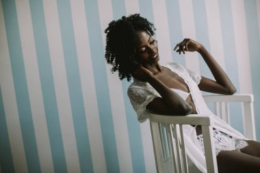 Genç ve güzel Afrikalı-Amerikalı kadın sandalyede oturuyordu