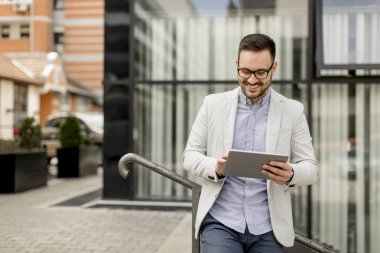 Ofis Binası tarafından dijital tablet ile yakışıklı genç işadamı