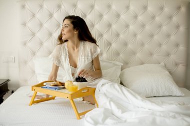 Genç ve güzel kadın yatak odası, yatakta kahvaltı