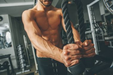 Çıplak gövde kaslı adam egzersizleri triceps ip ile yapıyor spor salonunda egzersiz
