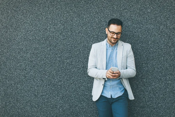 Schöner Junger Geschäftsmann Mit Handy Der Grauen Wand — Stockfoto