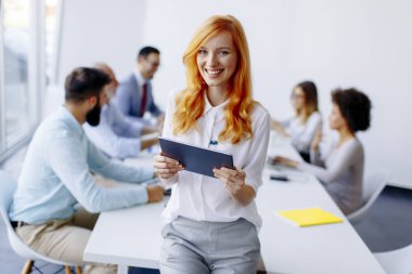 Dijital tablet modern ofis kullanan genç ve güzel kızıl saçlı kadın