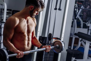 Genç adam kasları ile Halter salonunda esneme portresi