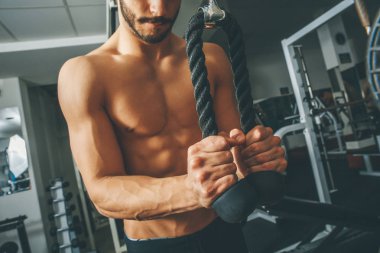 Çıplak gövde kaslı adam egzersizleri triceps ip ile yapıyor spor salonunda egzersiz