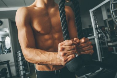 Çıplak gövde kaslı adam egzersizleri triceps ip ile yapıyor spor salonunda egzersiz