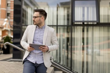 Ofis Binası tarafından dijital tablet ile yakışıklı genç işadamı