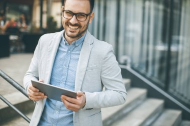 Ofis Binası tarafından dijital tablet ile yakışıklı genç işadamı