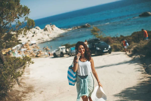 年轻漂亮的女人 与在夏天谈移动电话在海边的沙滩袋 — 图库照片