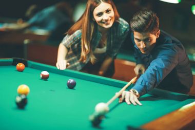 Genç çift barda bilardo oynuyor.