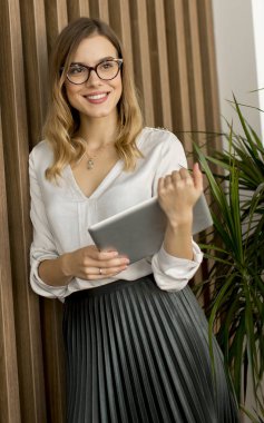 Genç çekici kadın Yöneticisi duran modern Office dijital tablet üzerinde çalışan