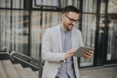 Ofis Binası tarafından dijital tablet ile yakışıklı genç işadamı