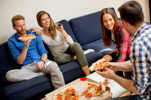Group of young friends eating pizza in the apartment