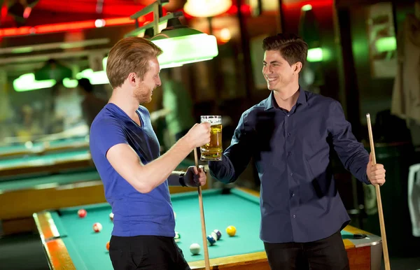 二人の若い男は彼の手でプールのスティックを押し ビールで乾杯 — ストック写真