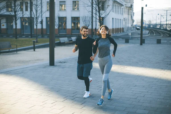 Healthy young couple running in the city with cityscape in background