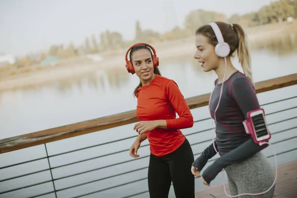 Two young women running by the river in the morning