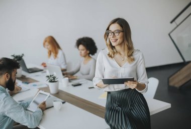 Genç çekici kadın Yöneticisi duran modern Office dijital tablet üzerinde çalışan