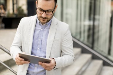 Ofis Binası tarafından dijital tablet ile yakışıklı genç işadamı