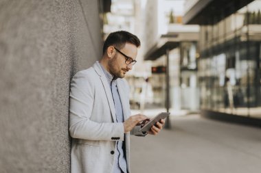 Dijital tablet kentsel ortamda açık tutan bir genç işadamı portresi