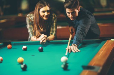 Genç çift barda bilardo oynuyor.