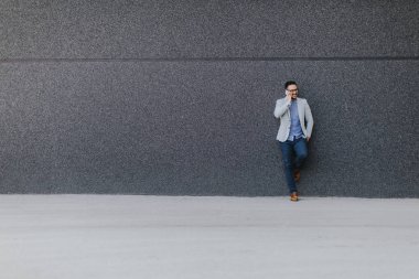 Genç adam cep telefonu el ile duvar tarafından açık duran