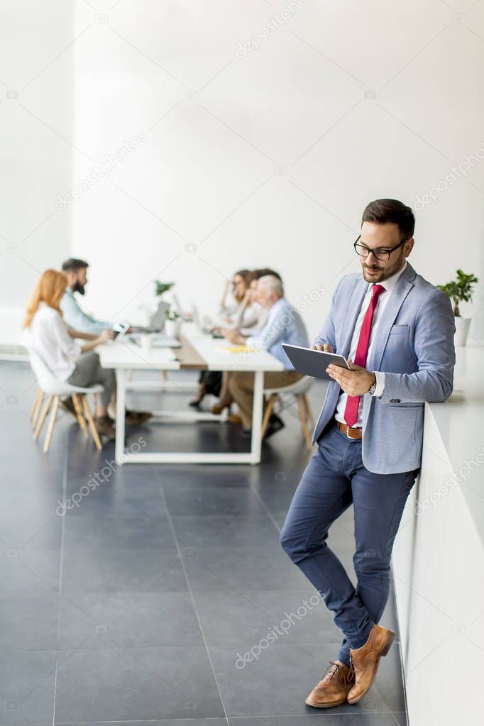 Portrait of young businessman with digital tablet in office